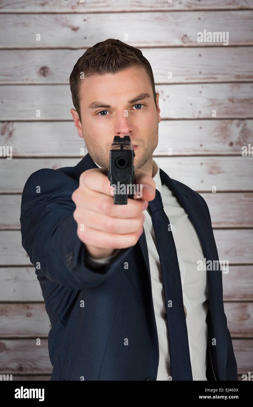 Composite image of serious businessman pointing a gun Stock Photo