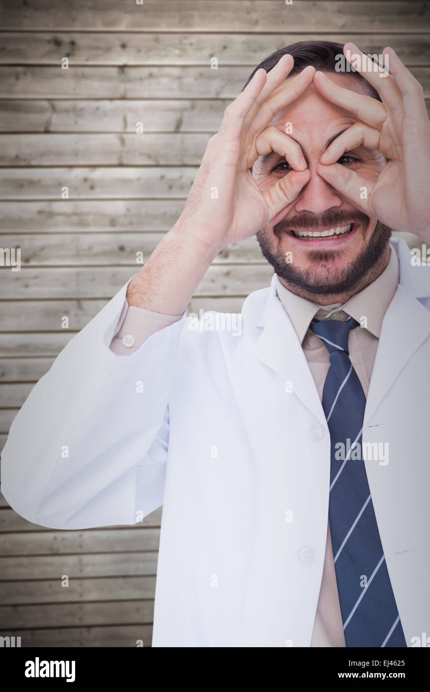 Composite image of smiling doctor forming eyeglasses with his hands Stock Photo