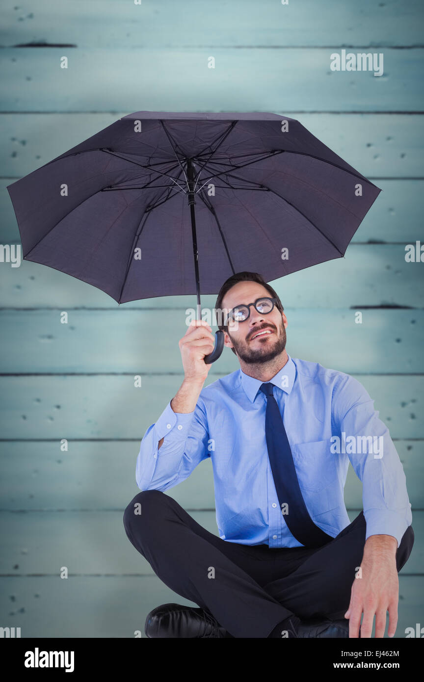 Composite image of businesswoman in suit sitting while holding umbrella Stock Photo