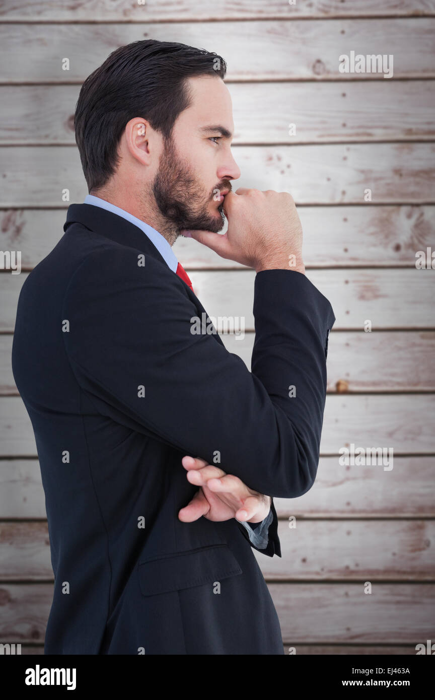 Composite image of thinking businessman standing with hand on chin Stock Photo