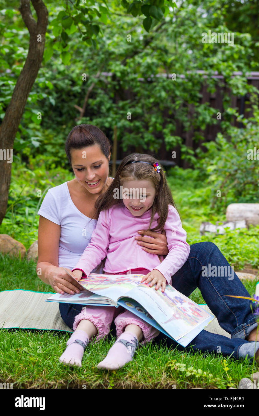 Mother and daughter read book outdoors education Stock Photo
