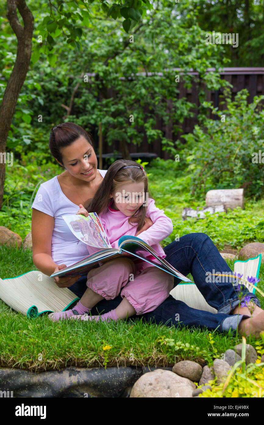 Mother and daughter read book outdoors education Stock Photo