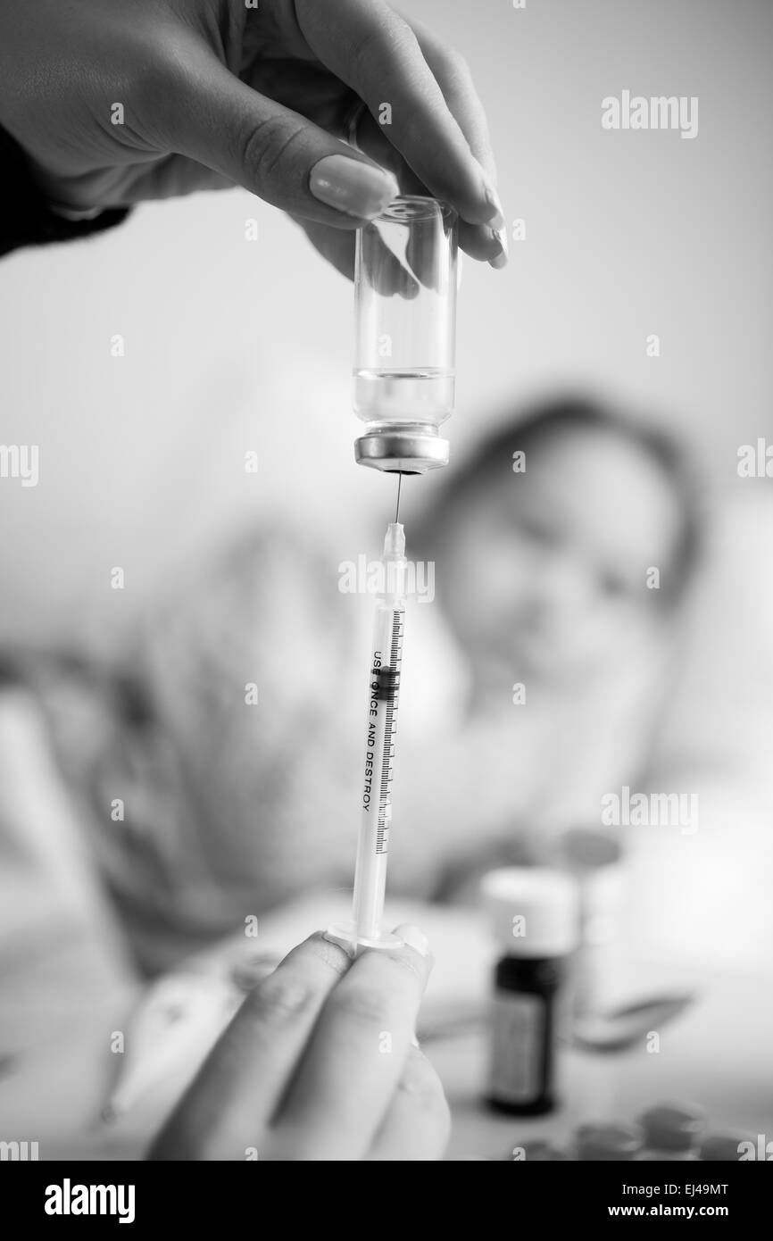 Black and white closeup photo of woman filling syringe from ampule Stock Photo