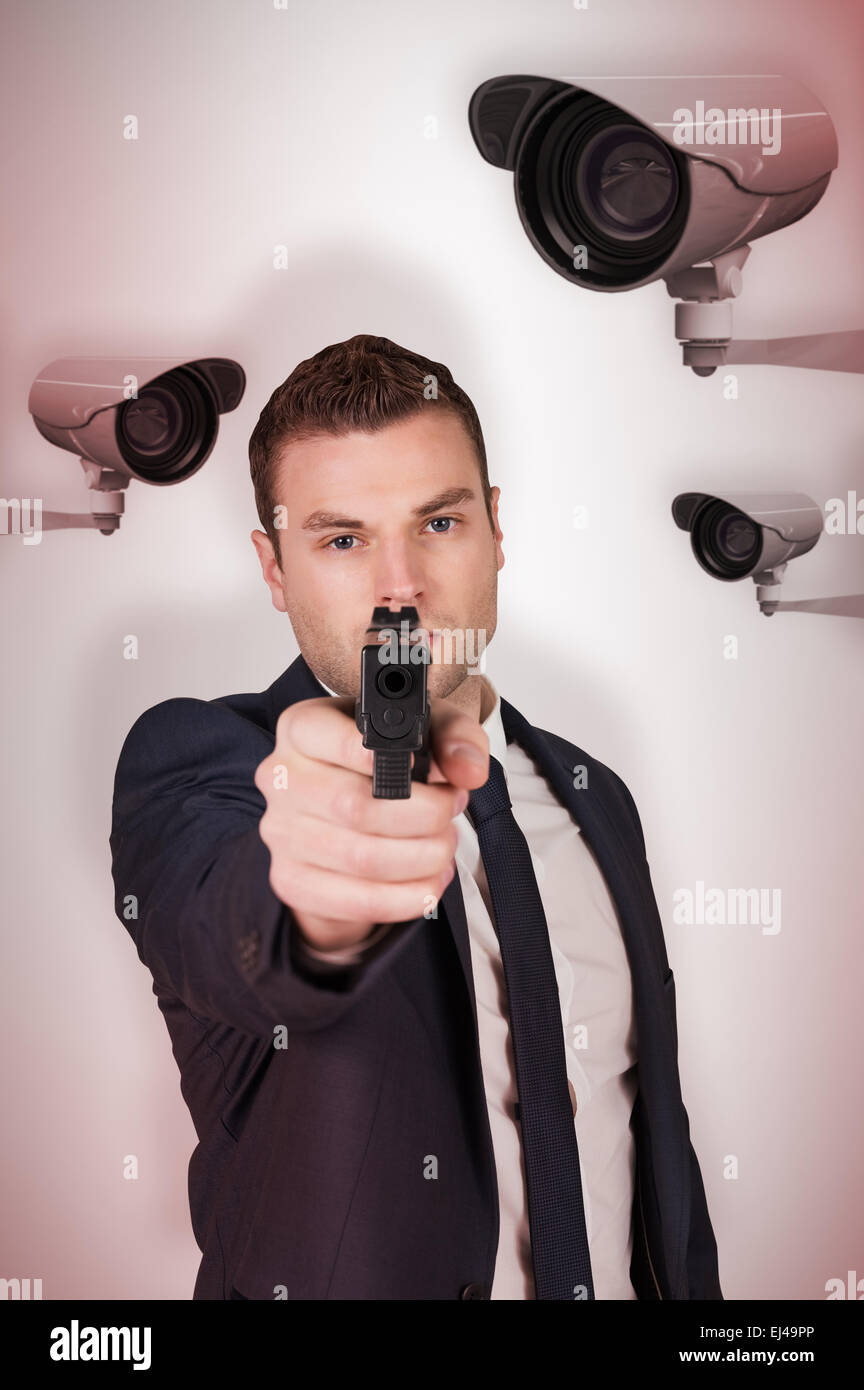 Composite image of serious businessman pointing a gun Stock Photo