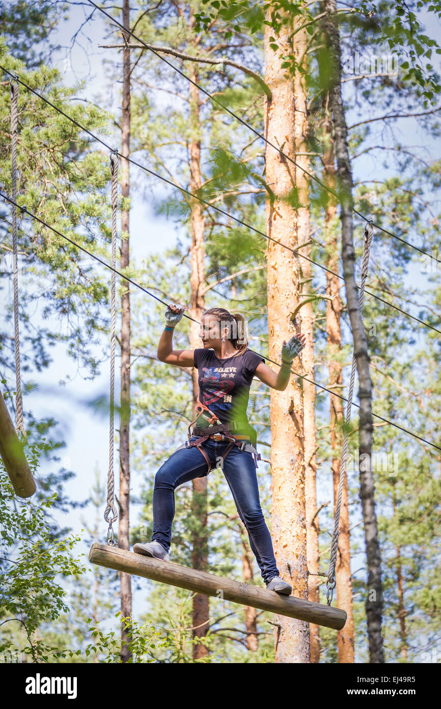 13 July 2014, Russia, Saint-Petersburg, adventure park 'Norwegian wood'. Young brave woman climbing in a adventure rope park Stock Photo