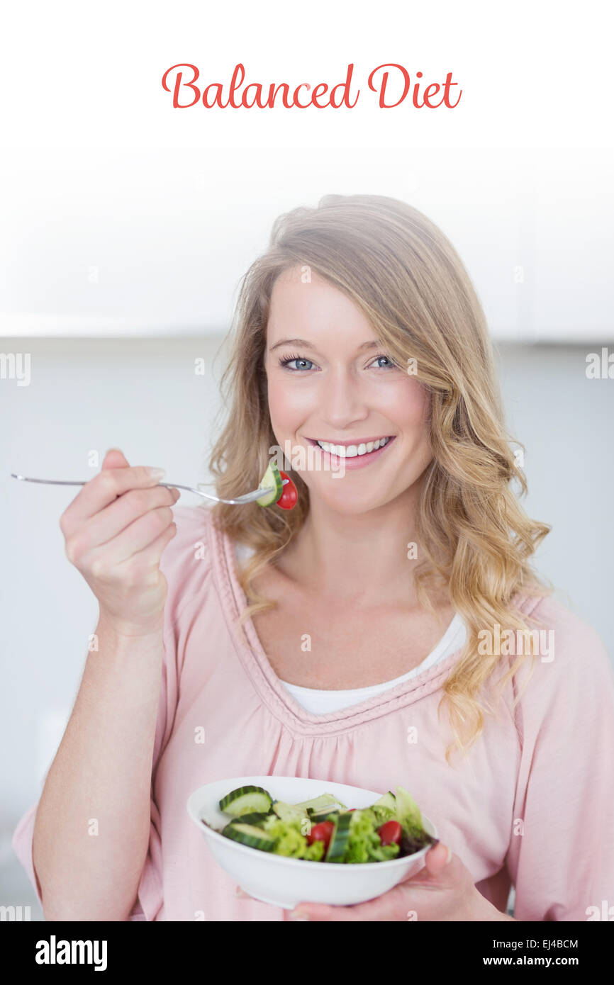 Balanced diet against woman having salad in kitchen Stock Photo
