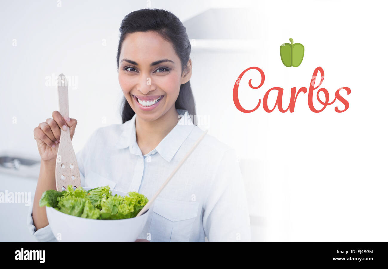 Carbs against beautiful smiling woman showing salad smiling at camera Stock Photo