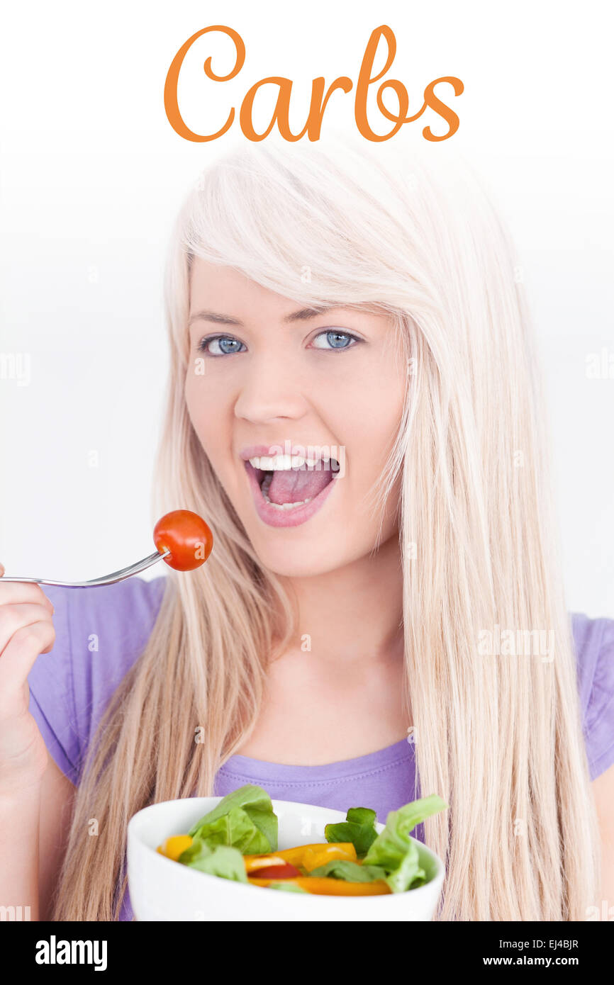 Carbs against gorgeous smiling woman eating her salad Stock Photo