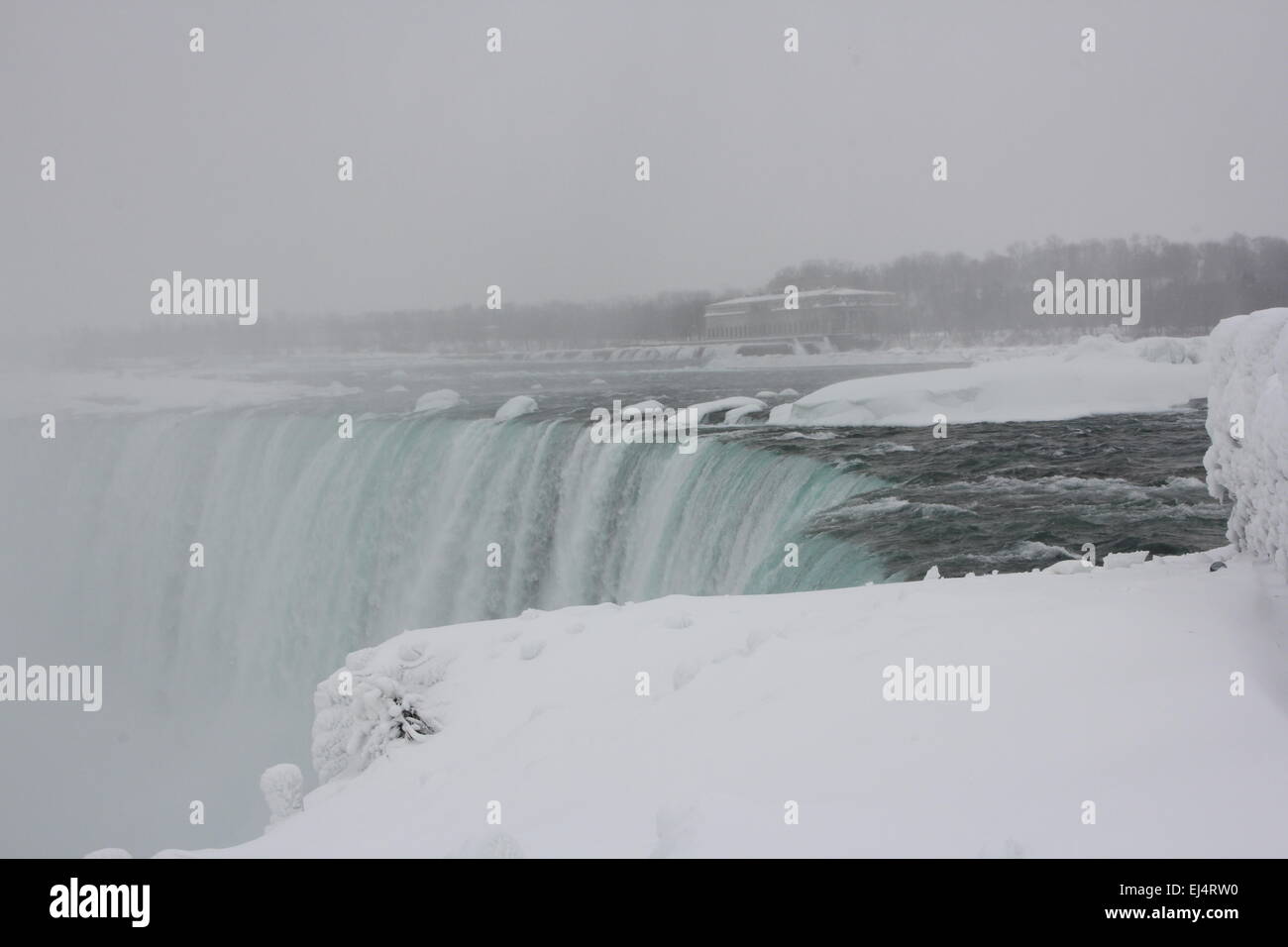 Horseshoe Falls at Niagara Falls, mist rising, during winter months. Ice formed above, below