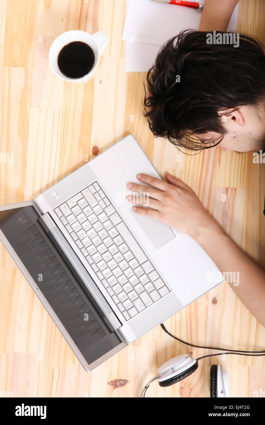 A Young Hispanic Man Falling Asleep At The Office Desk Stock Photo