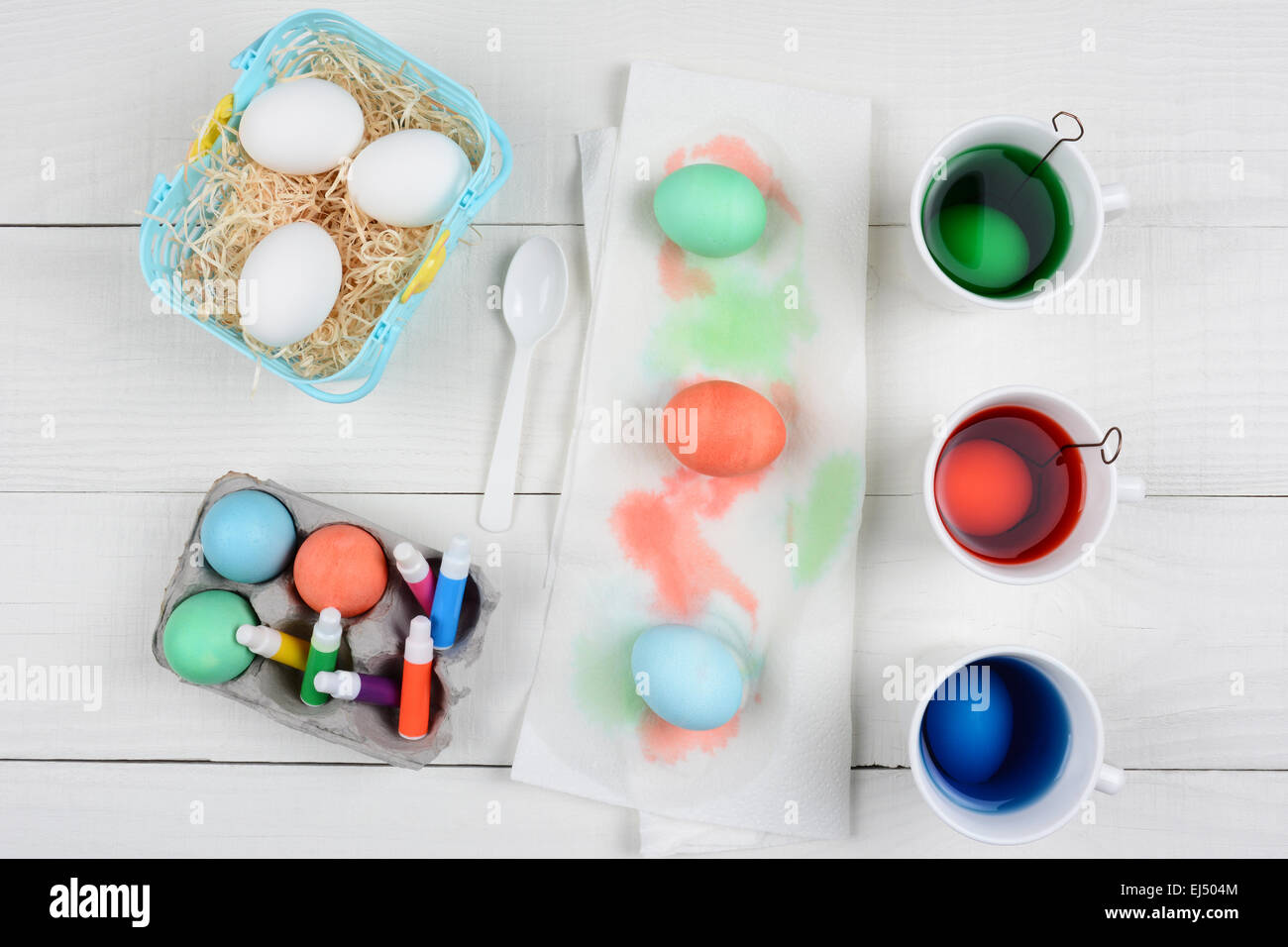 High angle still life shot of Easter Egg dying,cups full of dye, a basket of egg, dyed eggs, and markers for decoration. Stock Photo