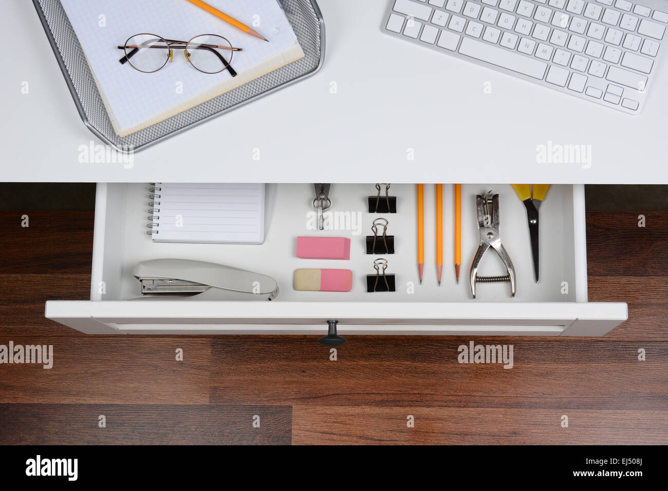 High angle shot of an open desk drawer showing the items inside. The