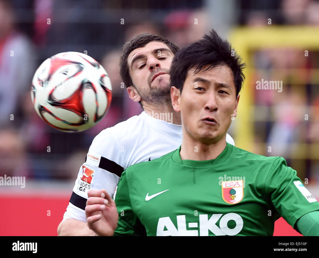 Freiburg, Germany. 21st Mar, 2015. Freiburg's Stefan Mitrovic (l) and Augsburg's Dong-Won Ji compete for the ball during the German Bundesliga soccer match between SC Freiburg and FC Augsburg at Schwarzwald-Stadion in Freiburg, Germany, 21 March 2015. PHOTO: ULI DECK/dpa (EMBARGO CONDITIONS - ATTENTION: Due to the accreditation guidelines, the DFL only permits the publication and utilisation of up to 15 pictures per match on the internet and in online media during the match.) © dpa/Alamy Live News Stock Photo
