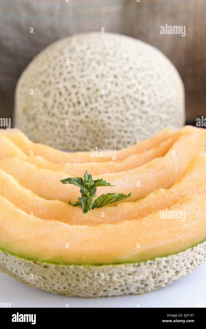 Sugar melon, cantaloupe or muskmelon wedges with a sprig of mint for