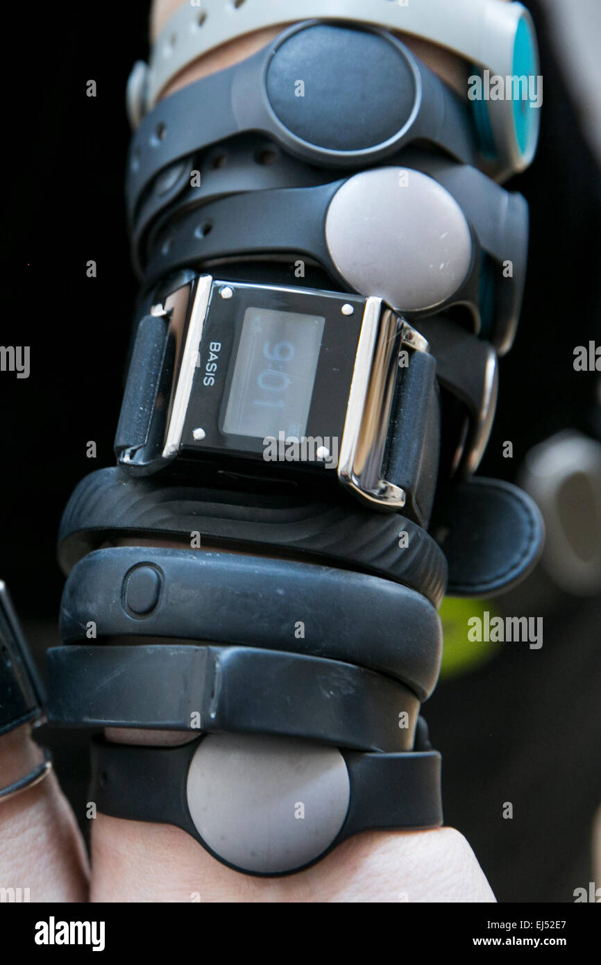 An individual is pictured wearing multiple wearable technology devices including the Nike FuelBand, Fitbit, Basis, Pebble, Jawbo Stock Photo