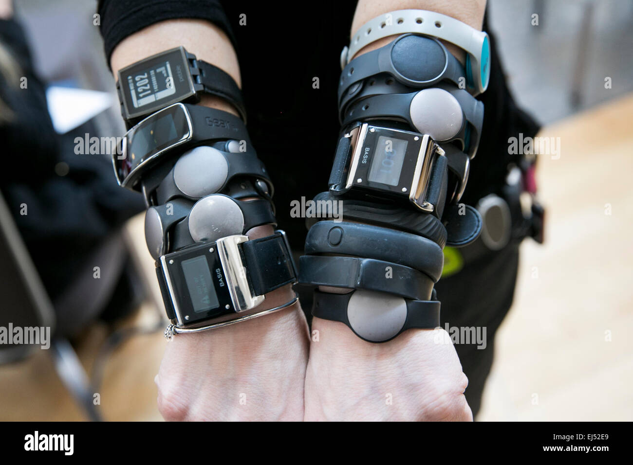 An individual is pictured wearing multiple wearable technology devices including the Nike FuelBand, Fitbit, Basis, Pebble, Jawbo Stock Photo