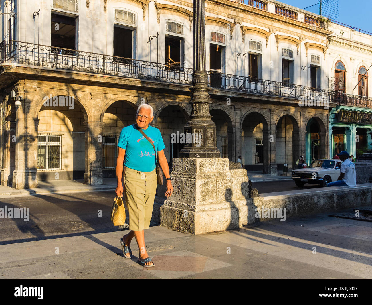 A male senior citizen with gray hair walks in the early morning light in Havana. Stock Photo