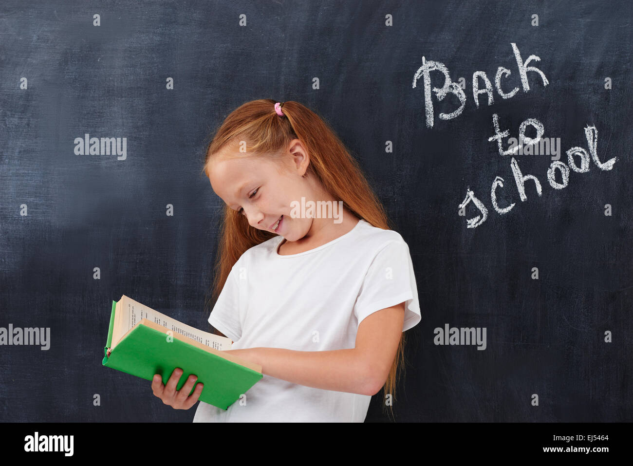Happy cute ginger school girl looking in the book Stock Photo