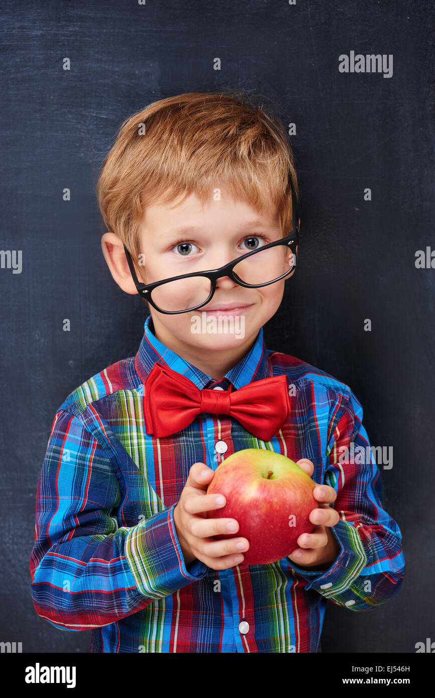 Mixed-up ginger primary school age boy holding red apple Stock Photo