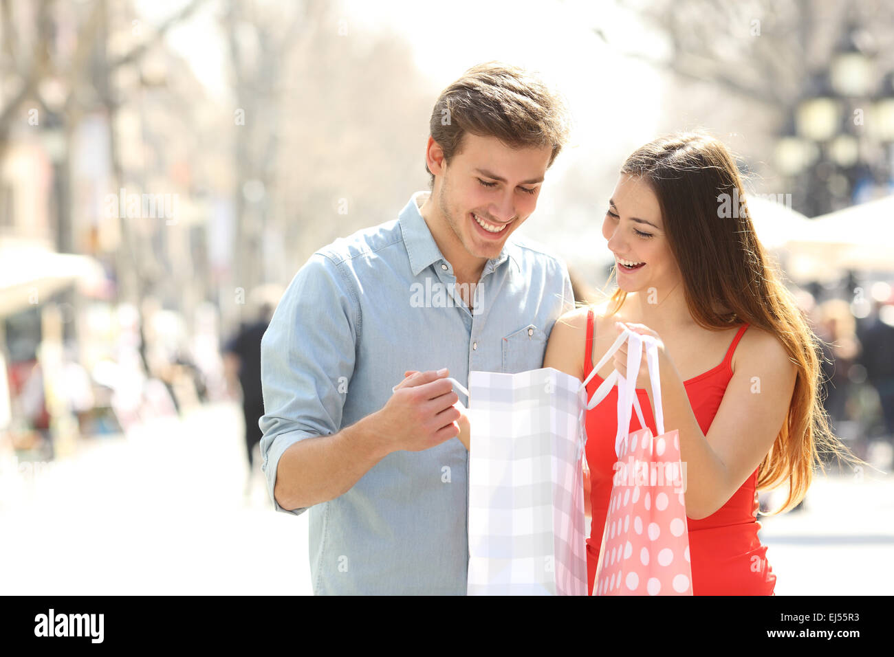 Couple shopping and holding bags while watching the products inside in the street Stock Photo
