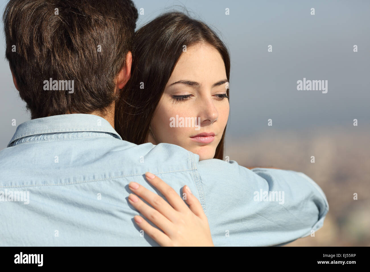 Sad woman hugging her boyfriend and looking down couple problems concept Stock Photo