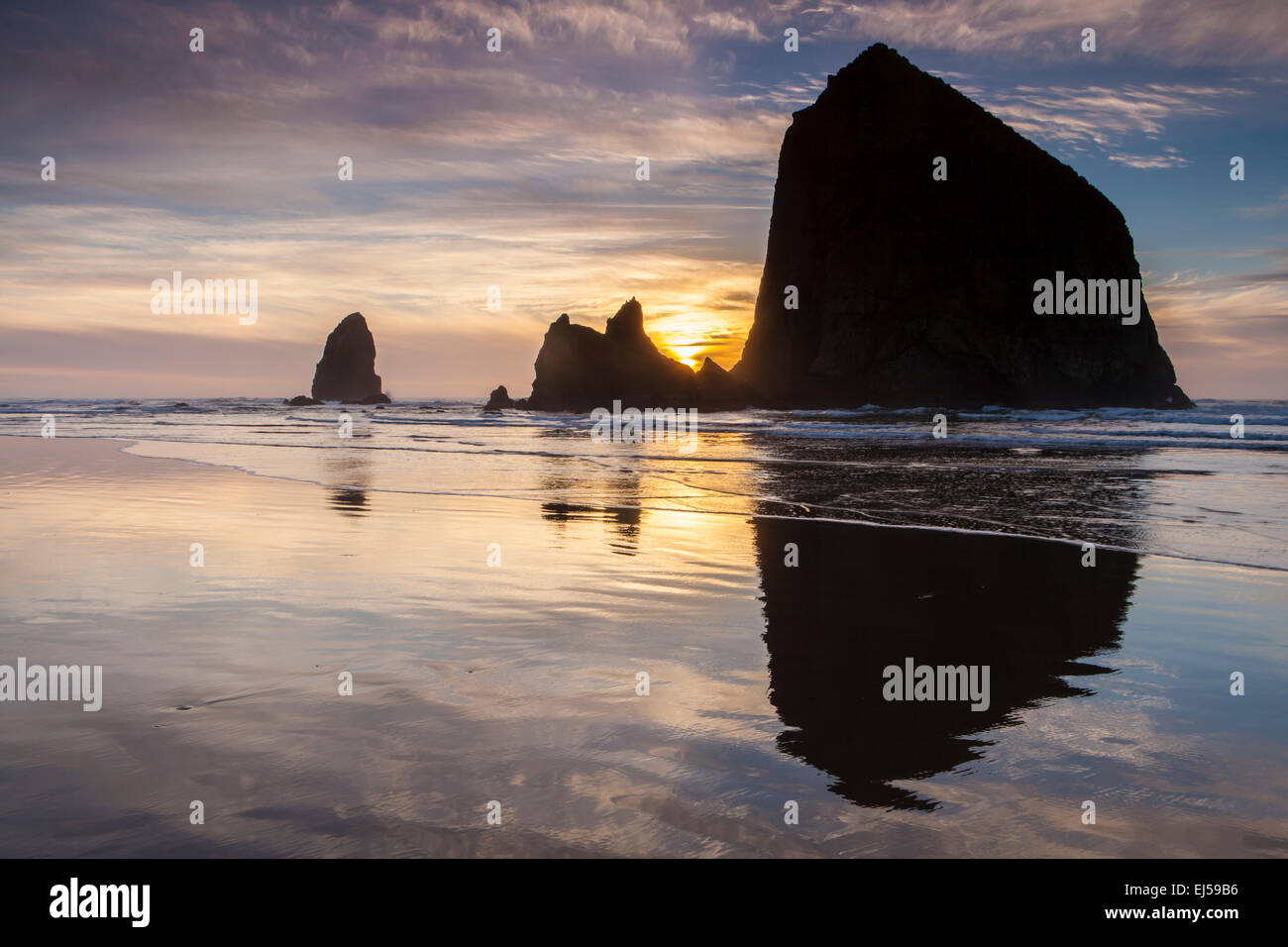 Sunset over Haystack Rock and other sea stacks at Cannon Beach, Oregon, USA. Stock Photo