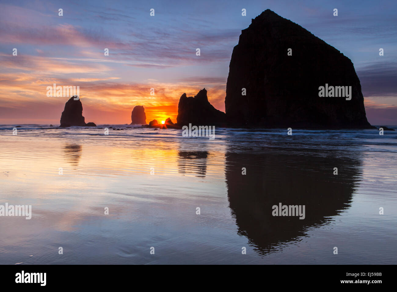 Sunset over Haystack Rock and other sea stacks at Cannon Beach, Oregon, USA. Stock Photo