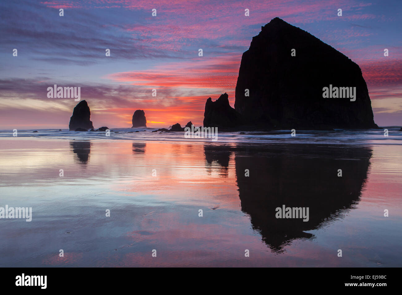 Sunset over Haystack Rock and other sea stacks at Cannon Beach, Oregon, USA. Stock Photo
