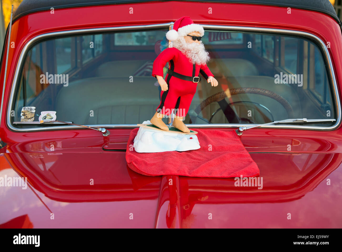 Surfing Santa Clause on a vintage red car hood, California, USA Stock Photo