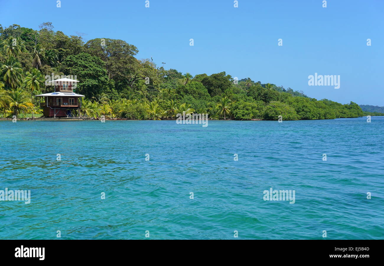 Off-grid oceanfront house and lush tropical vegetation on the coast of the Caribbean island of Bastimentos, Bocas del Toro, Pana Stock Photo