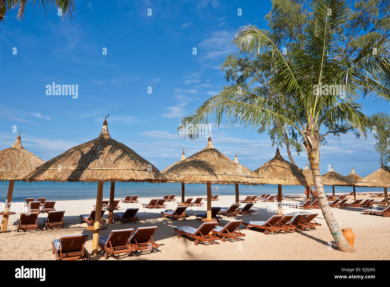 Lounge chairs and thatched parasols at the beach. Vinpearl Resort, Phu Quoc, Vietnam. Stock Photo