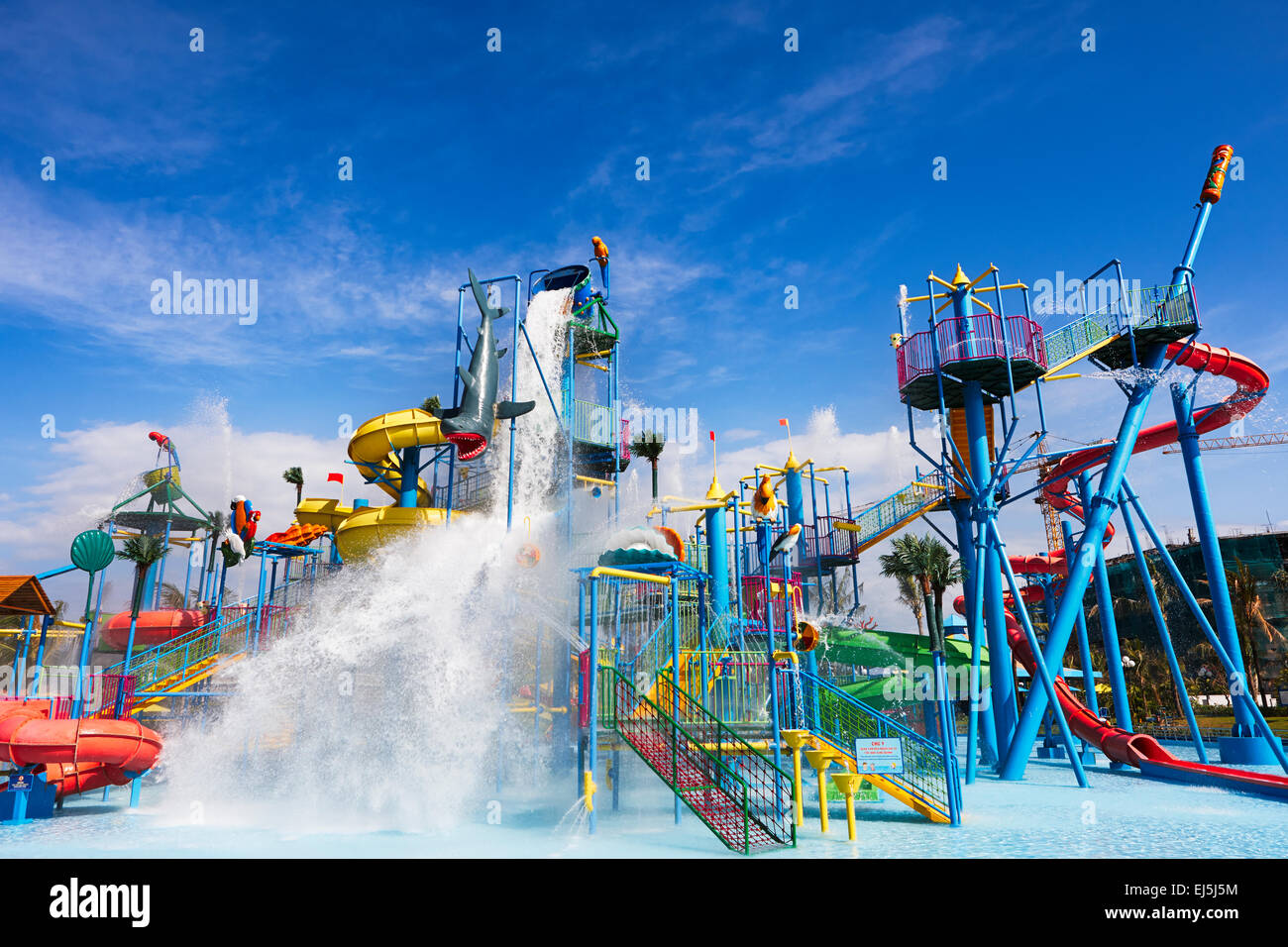 Water rushing down from giant swinging barrel on top of water sliding construction. Vinpearl Land Water Park, Phu Quoc island, Vietnam. Stock Photo