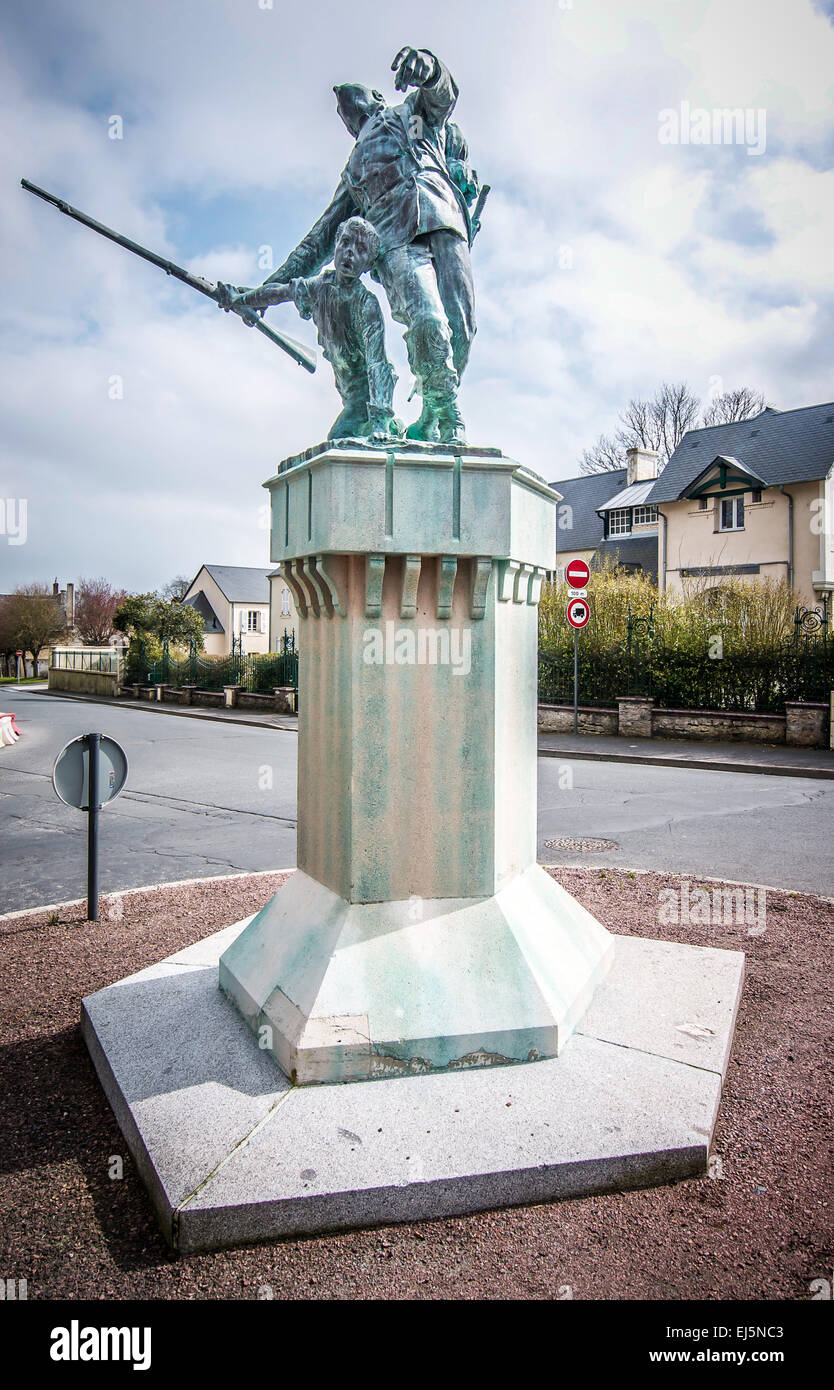 Poignant war memorial on a side street in Bayeux, Normandy, France. A soldier is shot & begins to fall, the young boy takes gun. Stock Photo