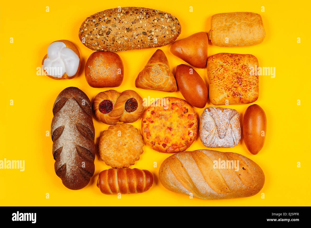 Assortment of bread and pastry composed on the yellow background Stock