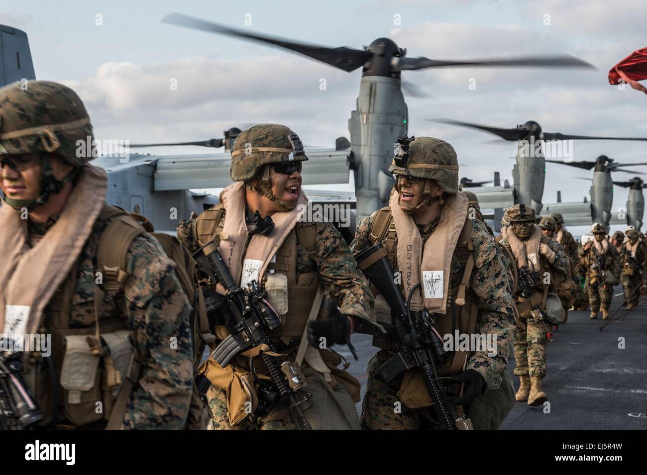 US Marines from the 31st Marine Expeditionary Unit prepare to board MV-22 Osprey tilt rotor aircraft on the flight deck of the amphibious assault ship USS Bonhomme Richard March 19, 2015 in the East China Sea. Stock Photo
