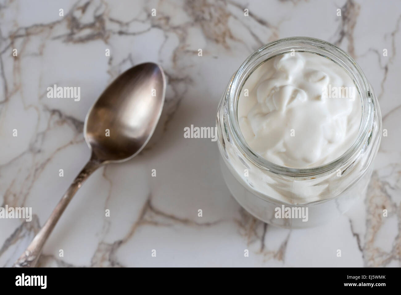 Close up of one jar with cream on kitchen table and one spoon Stock Photo