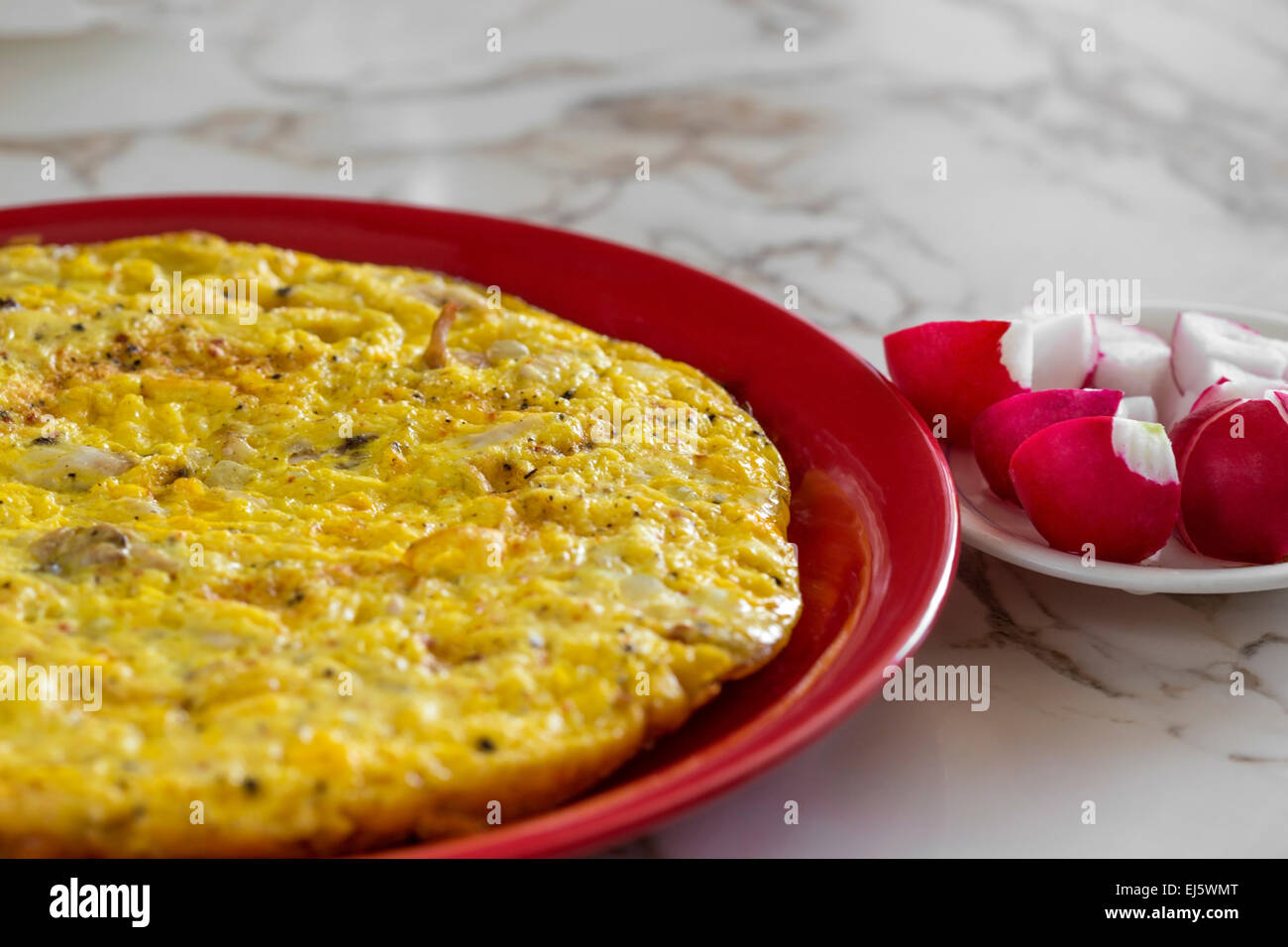 Omelet with cheese and radishes on a red plate Stock Photo