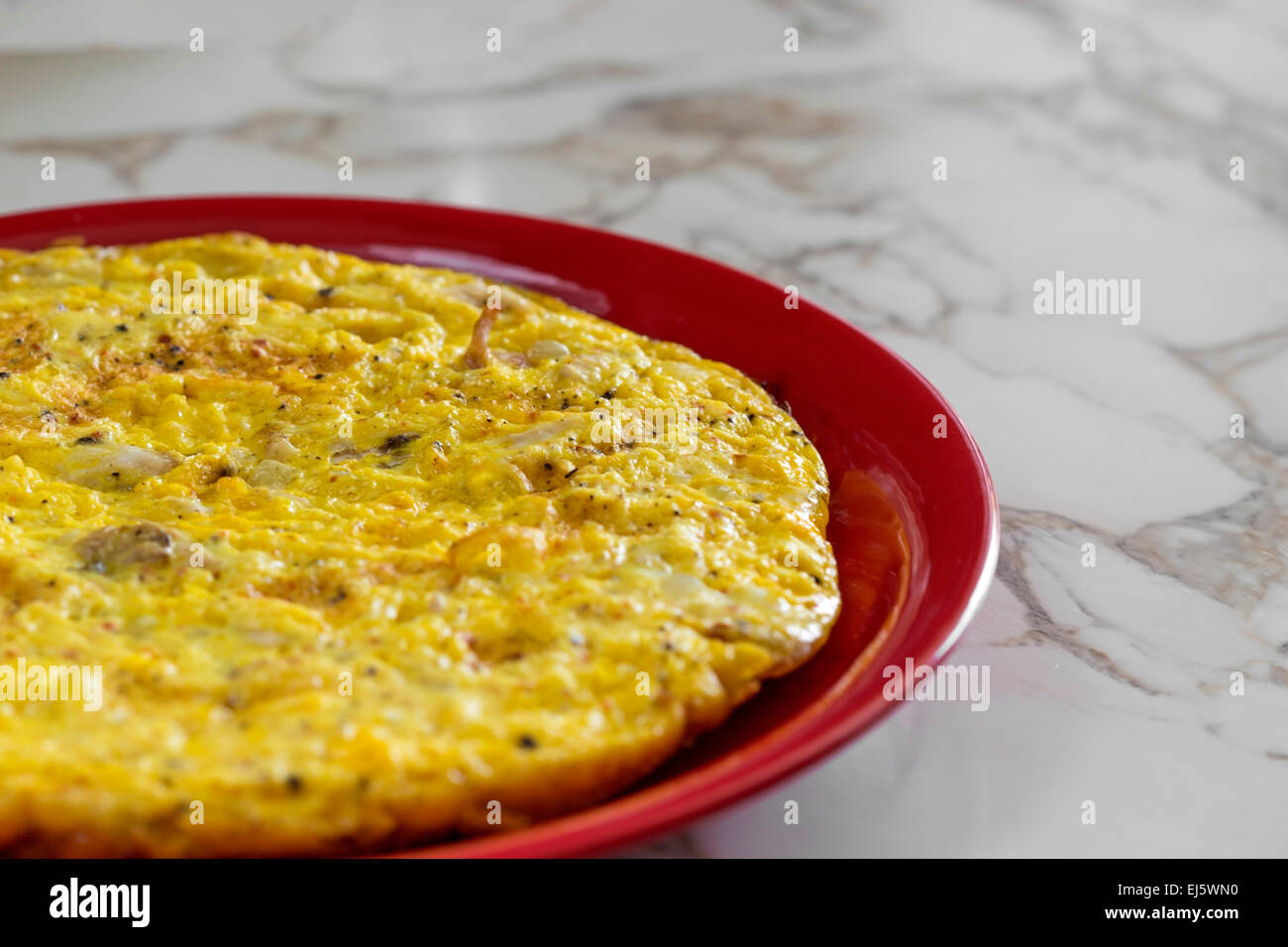 Omelet with cheese on a red plate Stock Photo