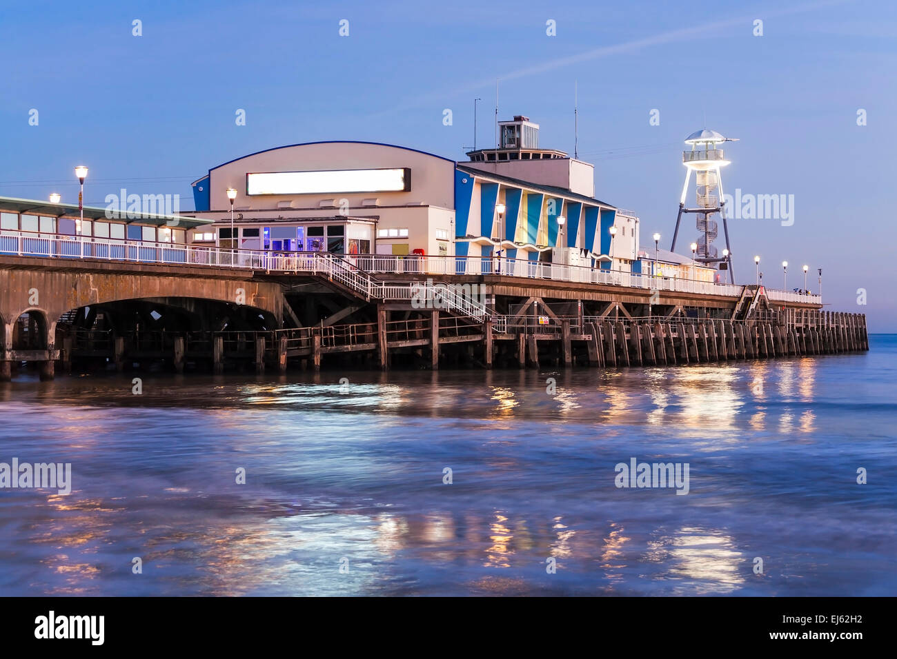 The lights of Bournemouth Pier at night reflected in the wet sand on