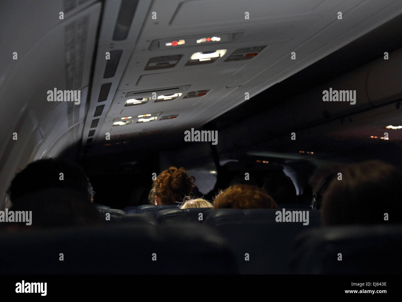 Airplane cabin with airline passengers and dimmed cabin lights during flight Stock Photo