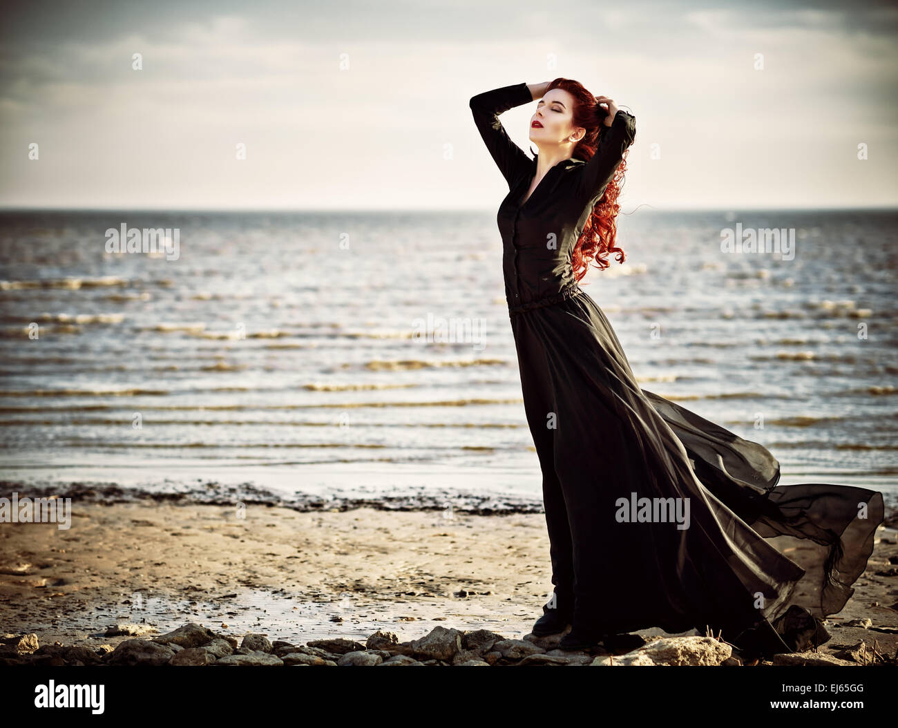 Beautiful goth girl standing on the sea beach Stock Photo