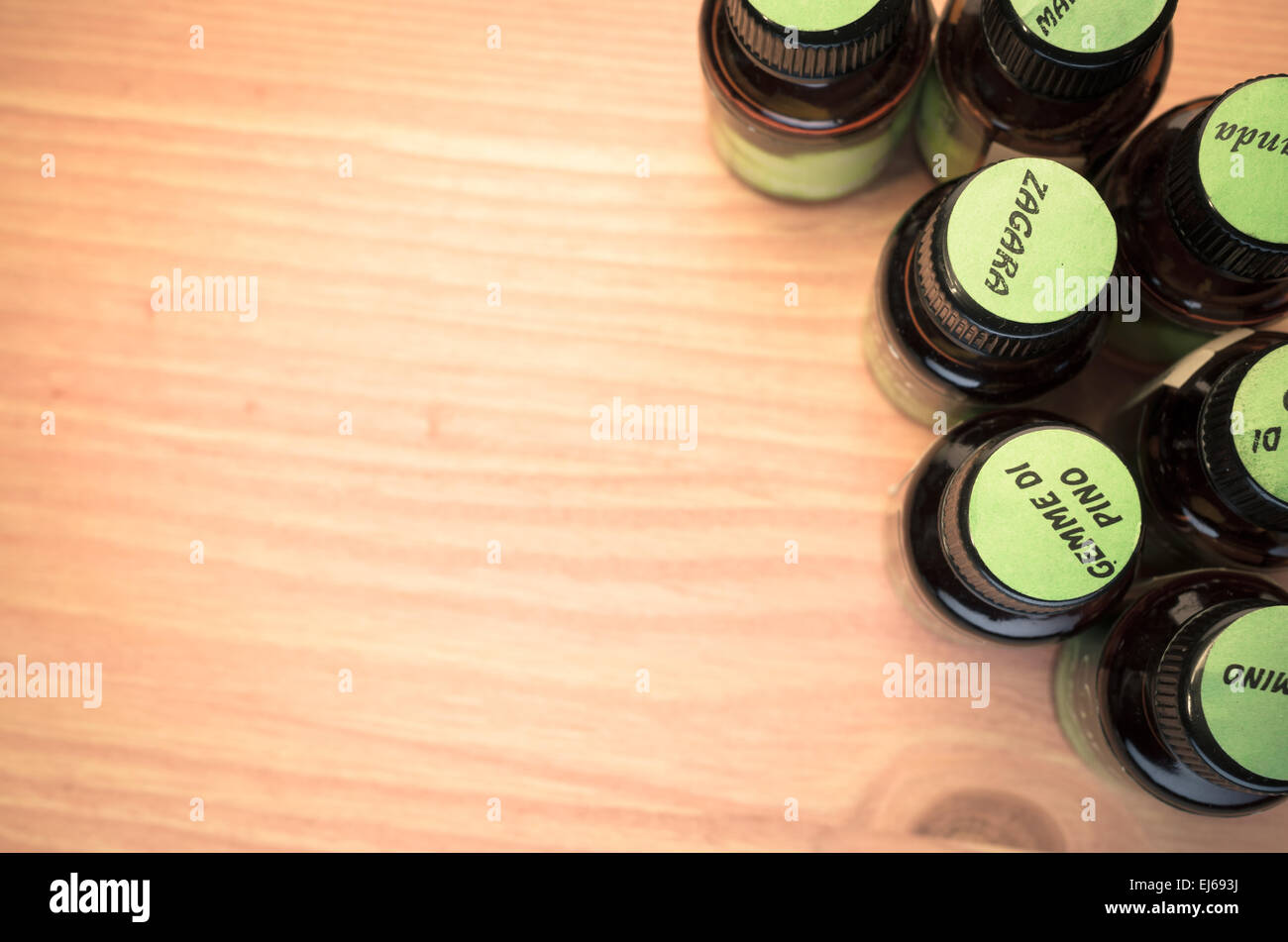 essential oils glass bottles with green labels on top - wood background