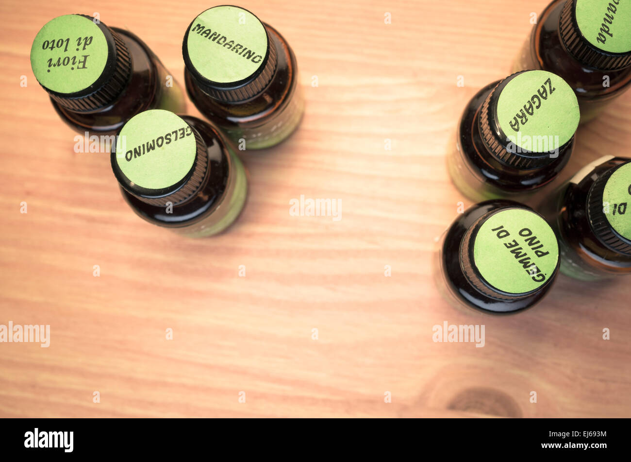 essential oils glass bottles with green labels on top - wood background