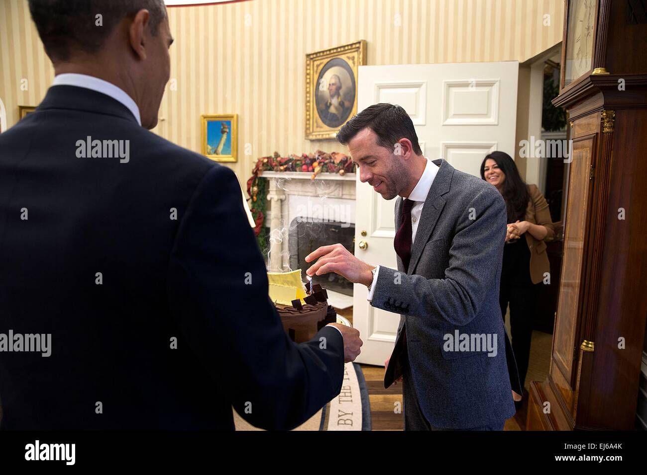 US President Barack Obama presents a birthday cake to Brian Mosteller, Director of Oval Office Operations, in the Oval Office of the White House December 5, 2014 in Washington, DC. Stock Photo