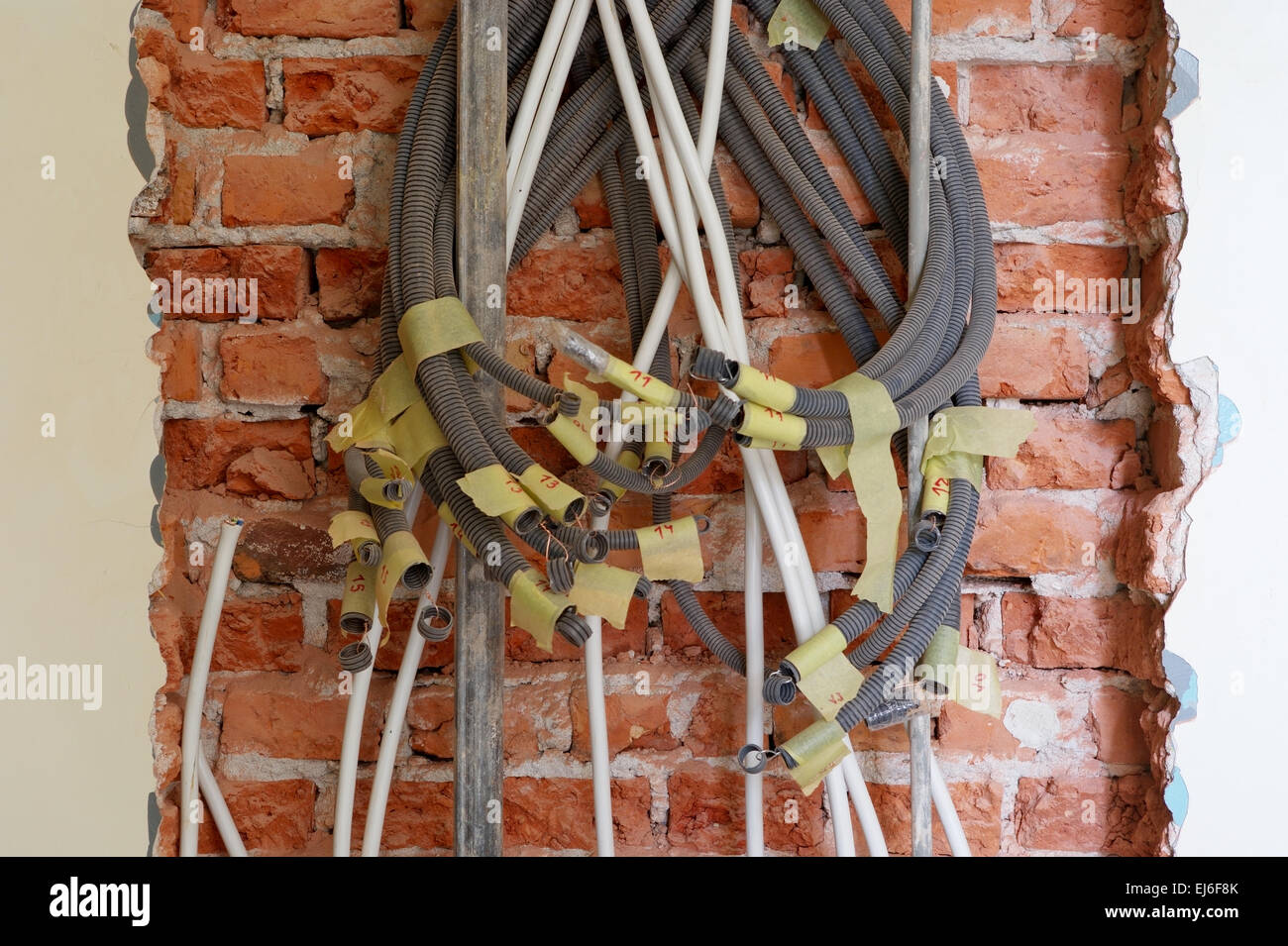Entwined tangled electrical conduits on the brick wall during
