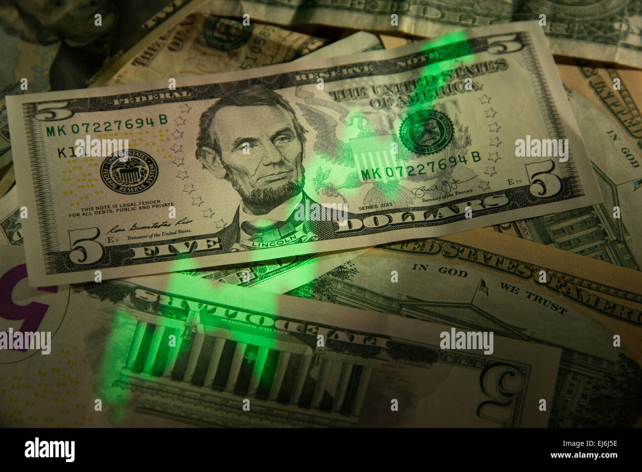 A green 'stock market chart' projected on a pile of American Dollars. Stock Photo