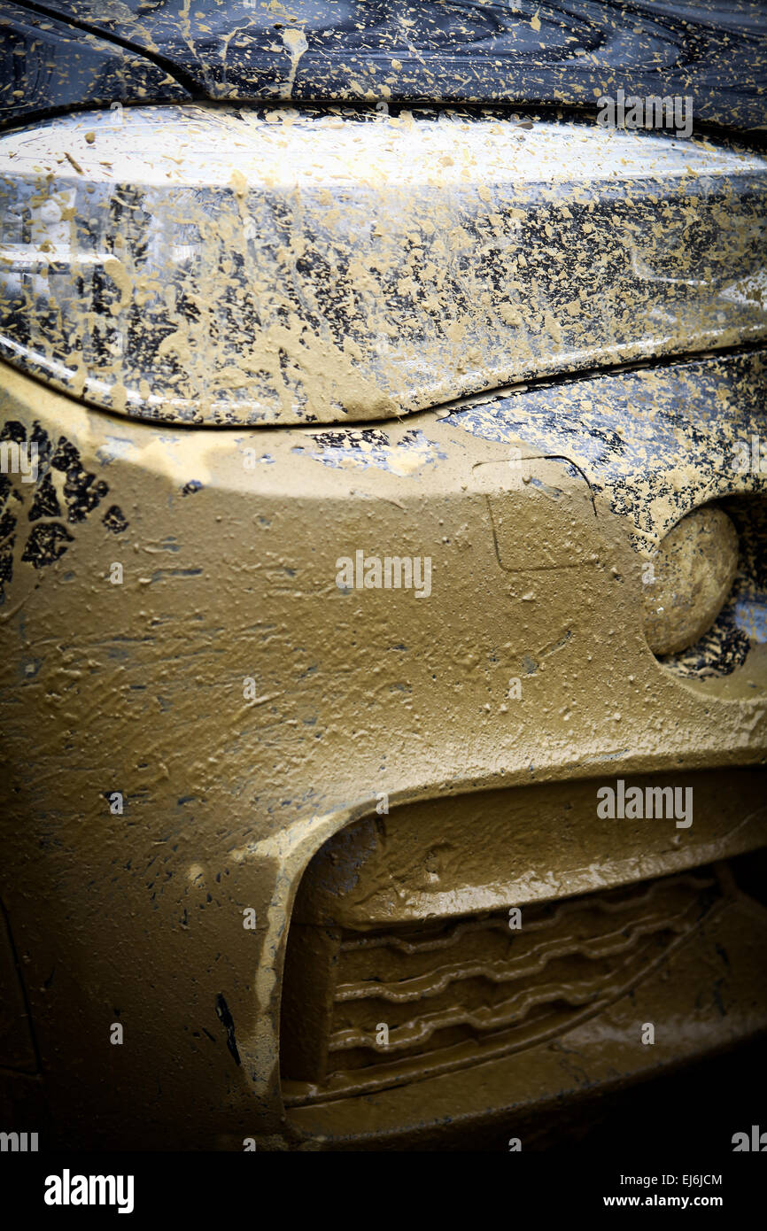 Color detail with the front side of an offroad car, covered in mud