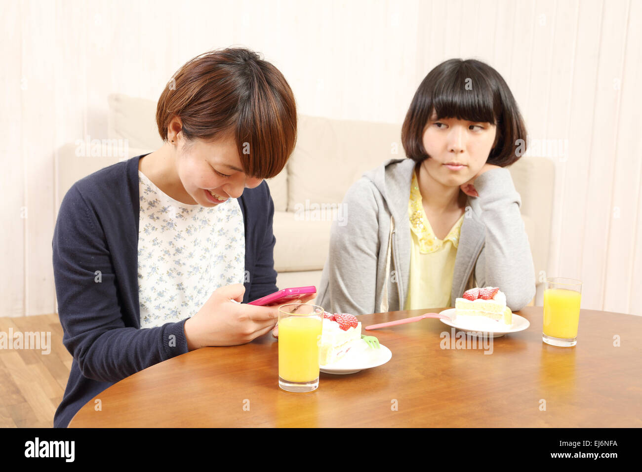 Young Japanese girls having a piece of cake together in the living room Stock Photo