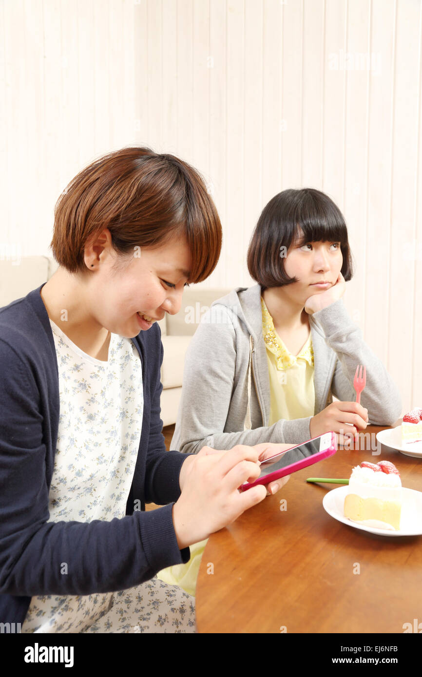 Young Japanese girls having a piece of cake together in the living room Stock Photo