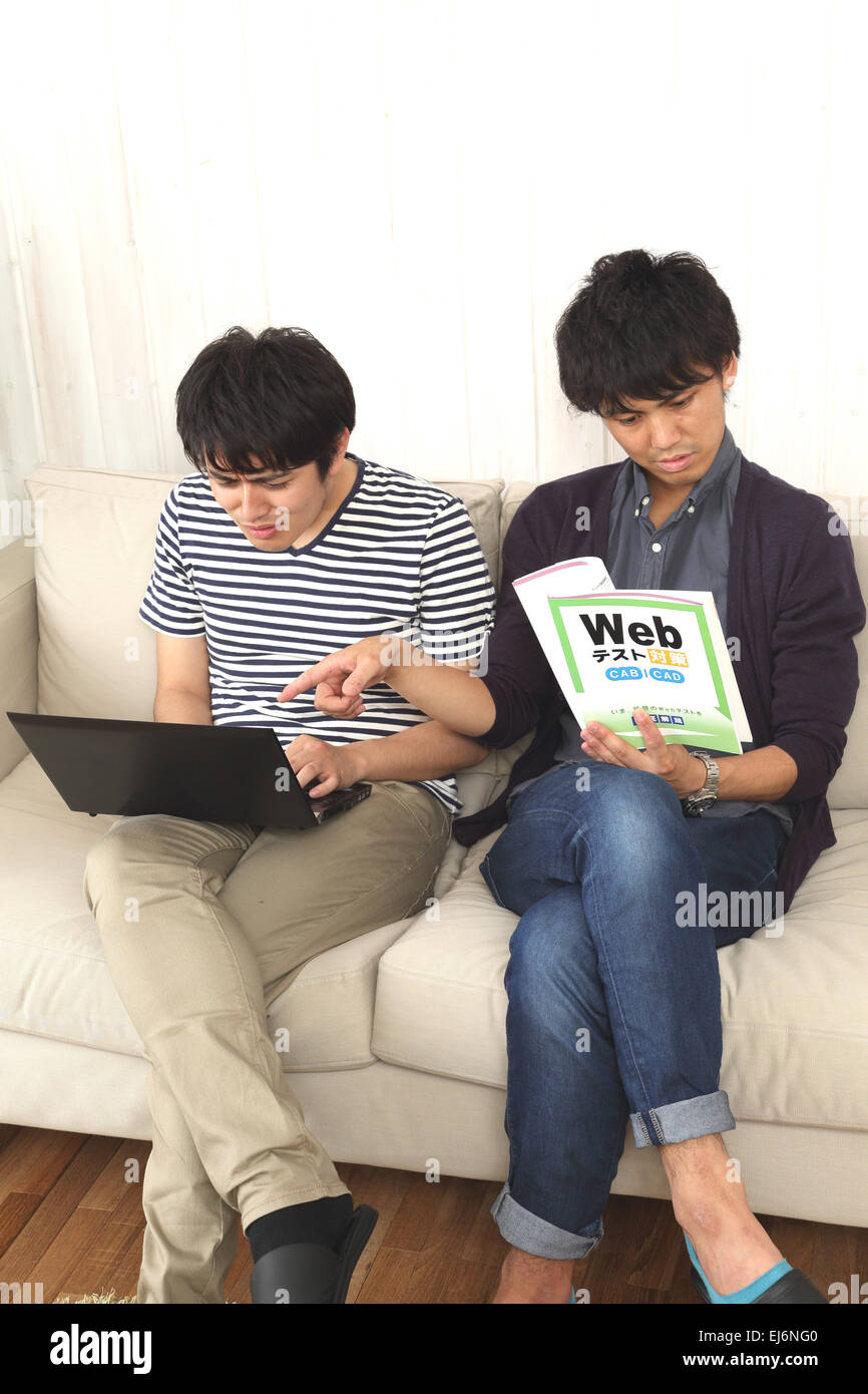 Young Japanese men working with laptop on the sofa Stock Photo